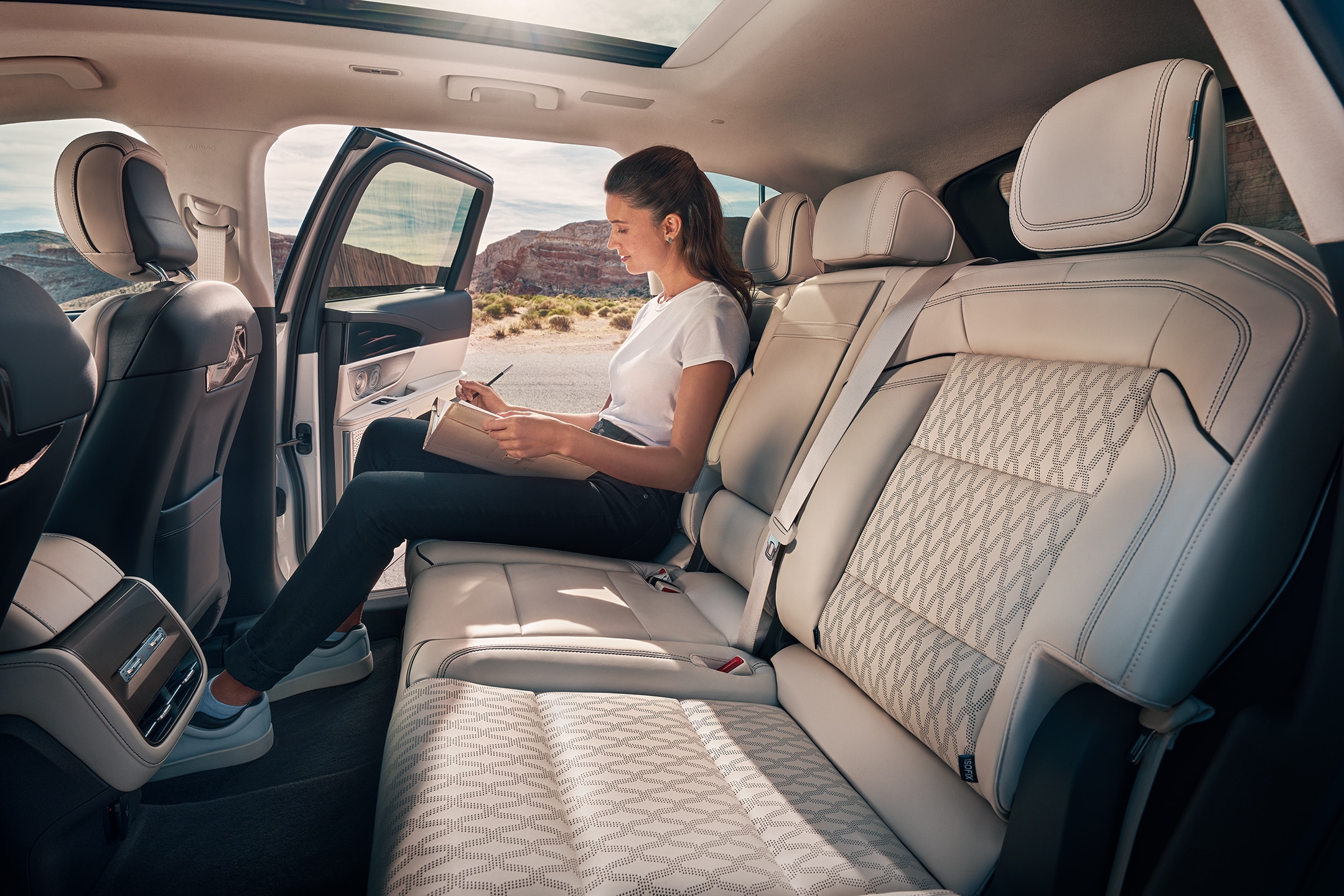 Una persona se toma un momento de relax en la segunda fila de una SUV Lincoln Black Label Nautilus® 2024.