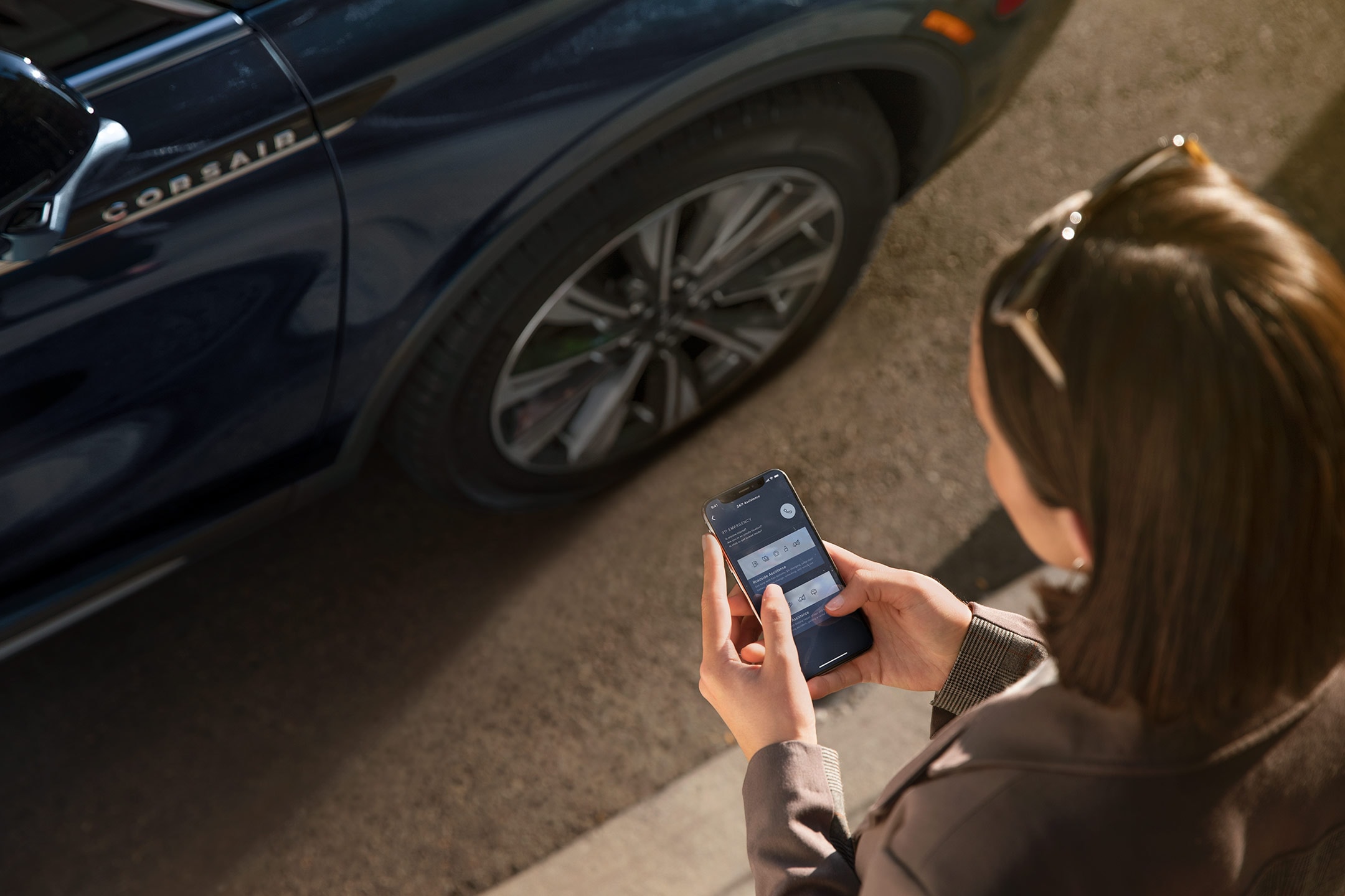 Una persona interactúa con la aplicación Lincoln Way® en su smartphone mientras se acerca a su vehículo Lincoln.