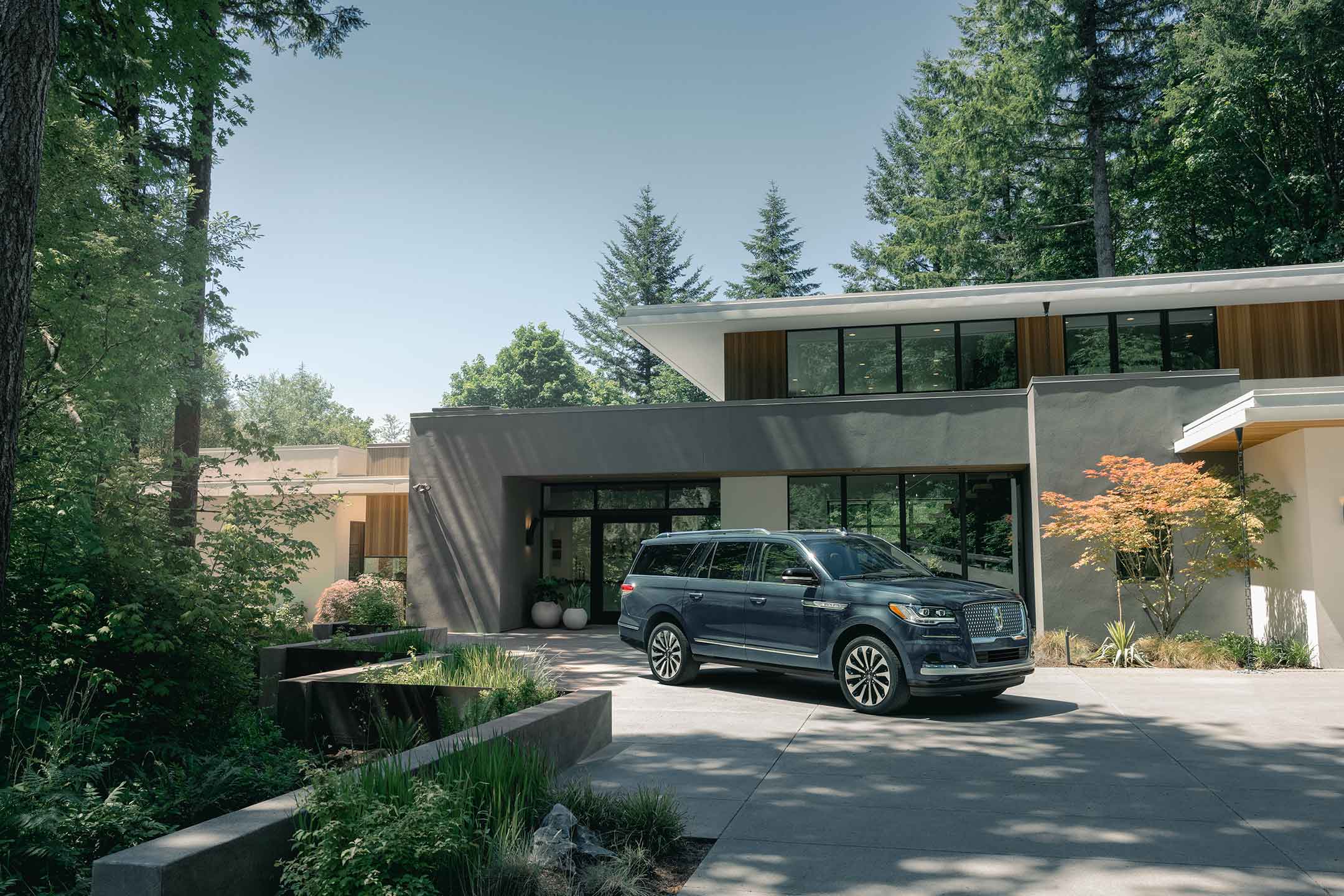 A 2024 Lincoln Navigator® SUV is parked in front of a beautiful mid-century modern home on a sunny day.